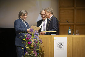 Drei Männer stehen hinter einem Podium.