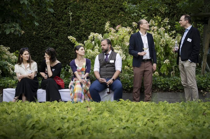 Männer und Frauen unterhalten sich im Garten der Akademie.