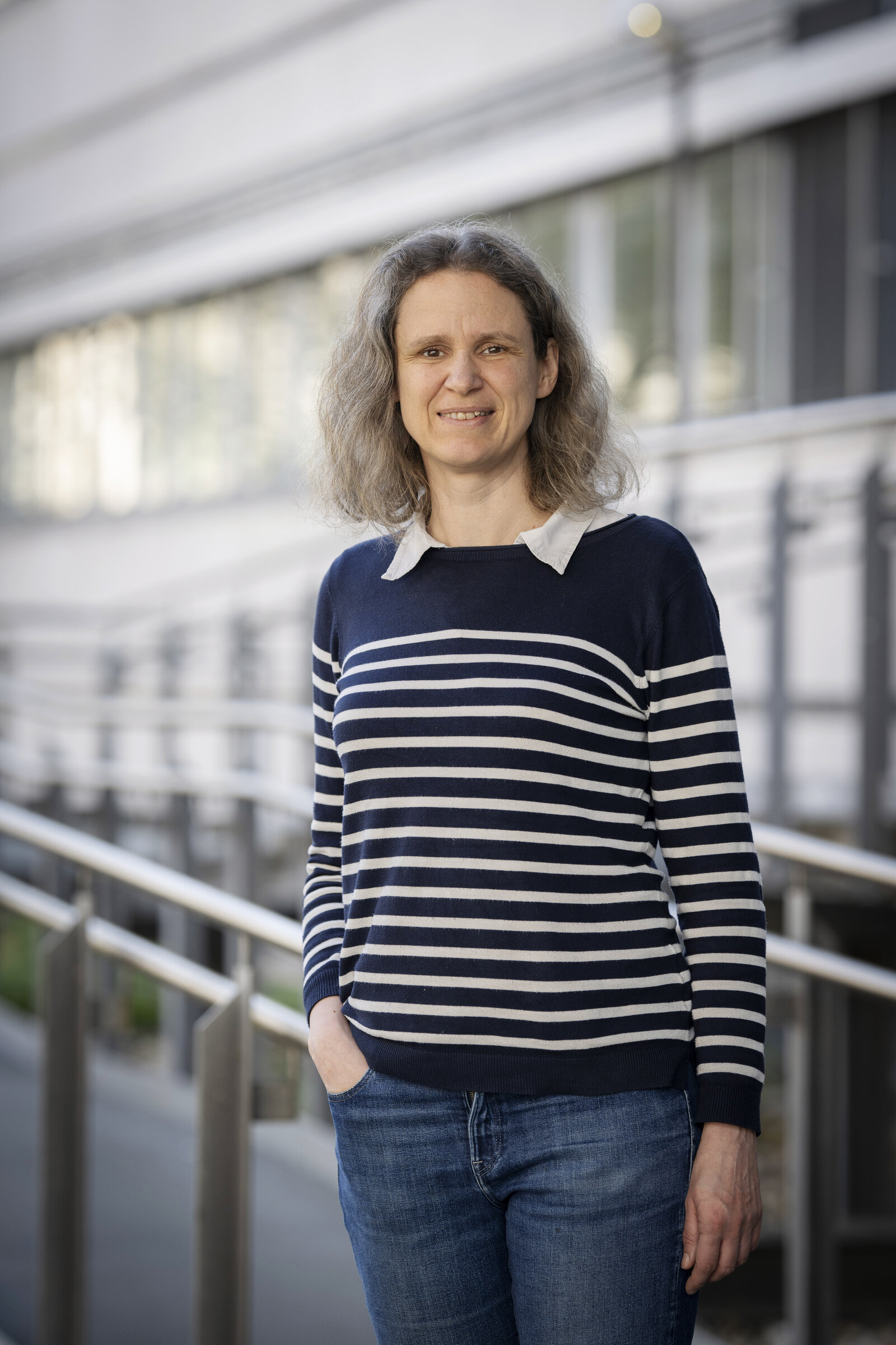 Eine Frau in einem blau-weißen Pullover schaut in die Kamera.