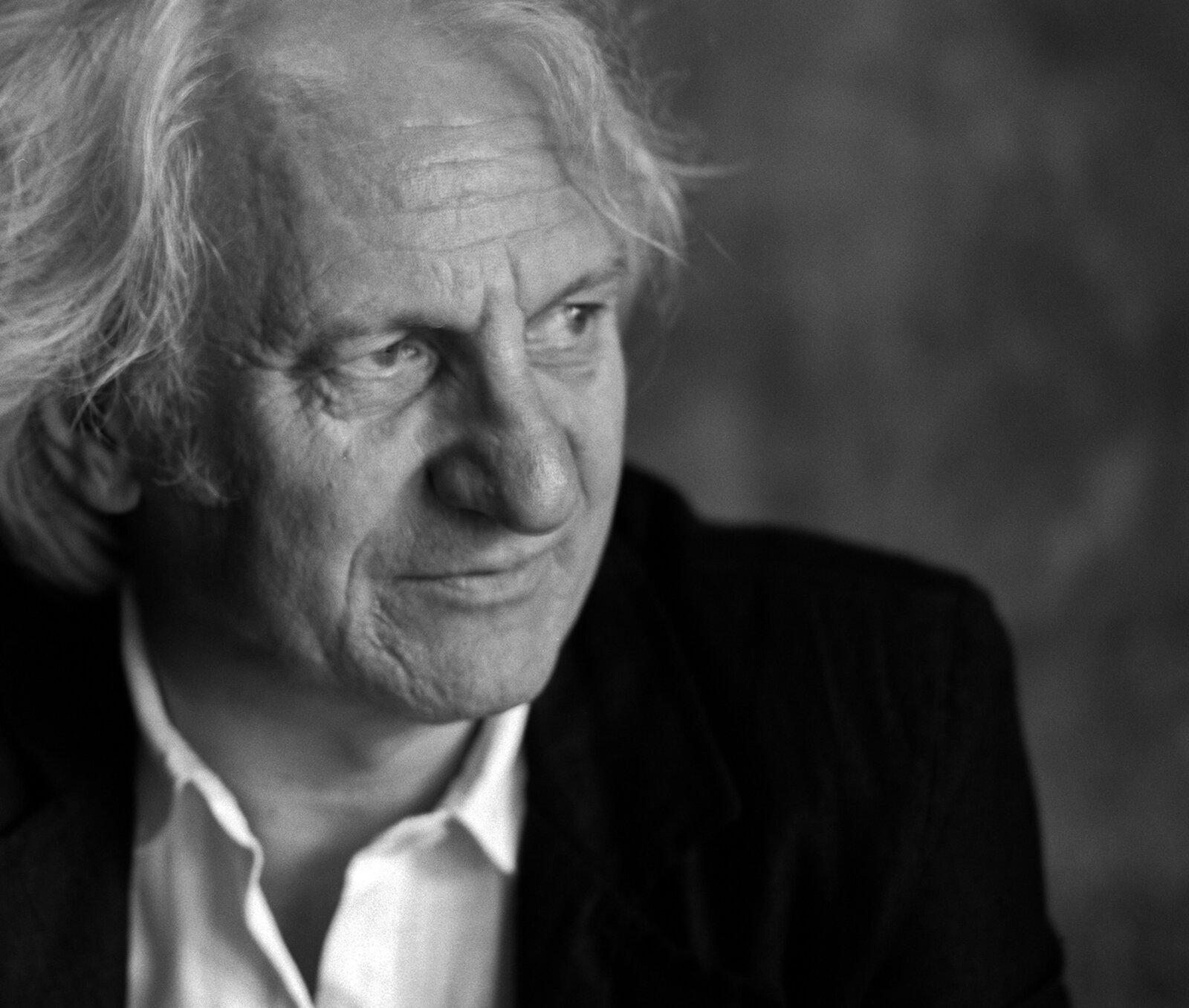 Ein Mann schaut nach rechts. Er trägt eine Anzugjacke.