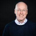 Ein Mann mit Brille lächelt strahlend in die Kamera.