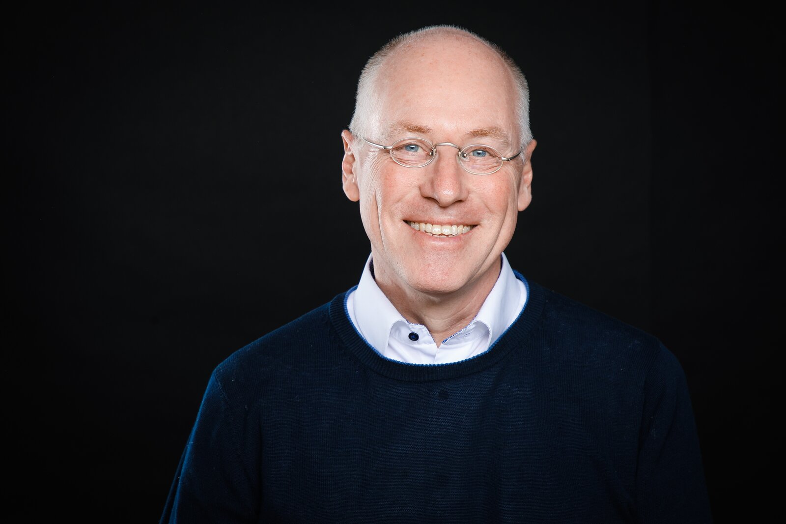 Ein Mann mit Brille lächelt strahlend in die Kamera.