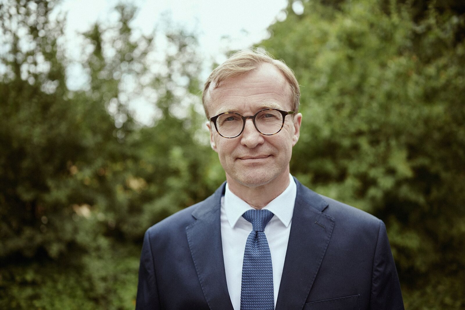 Ein Mann steht vor Strauchern.