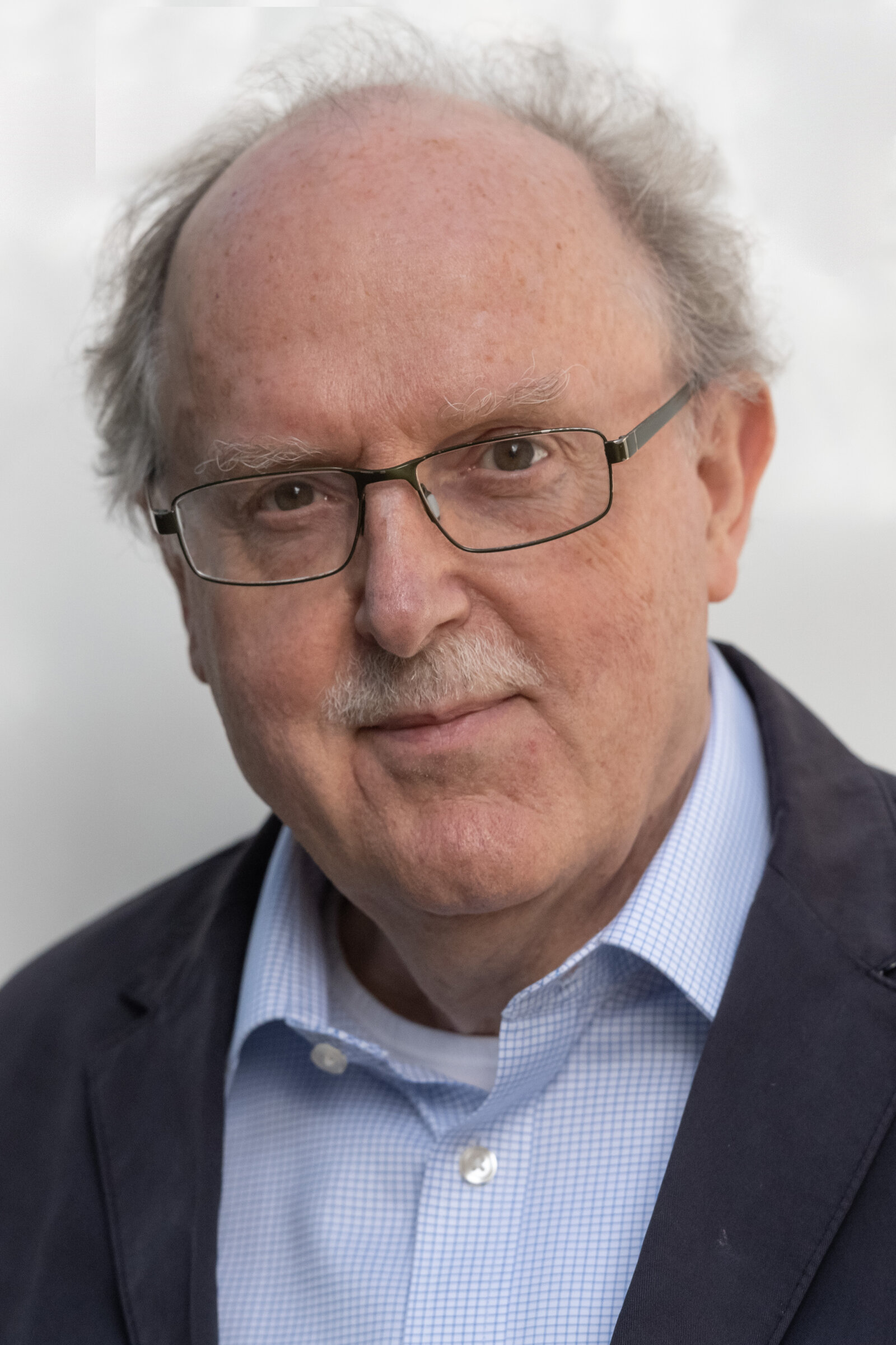 Mann mit Brille und OBerlippenbart lächelt.