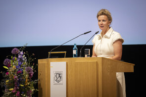Eine Frau steht an einem Rednerpult. 