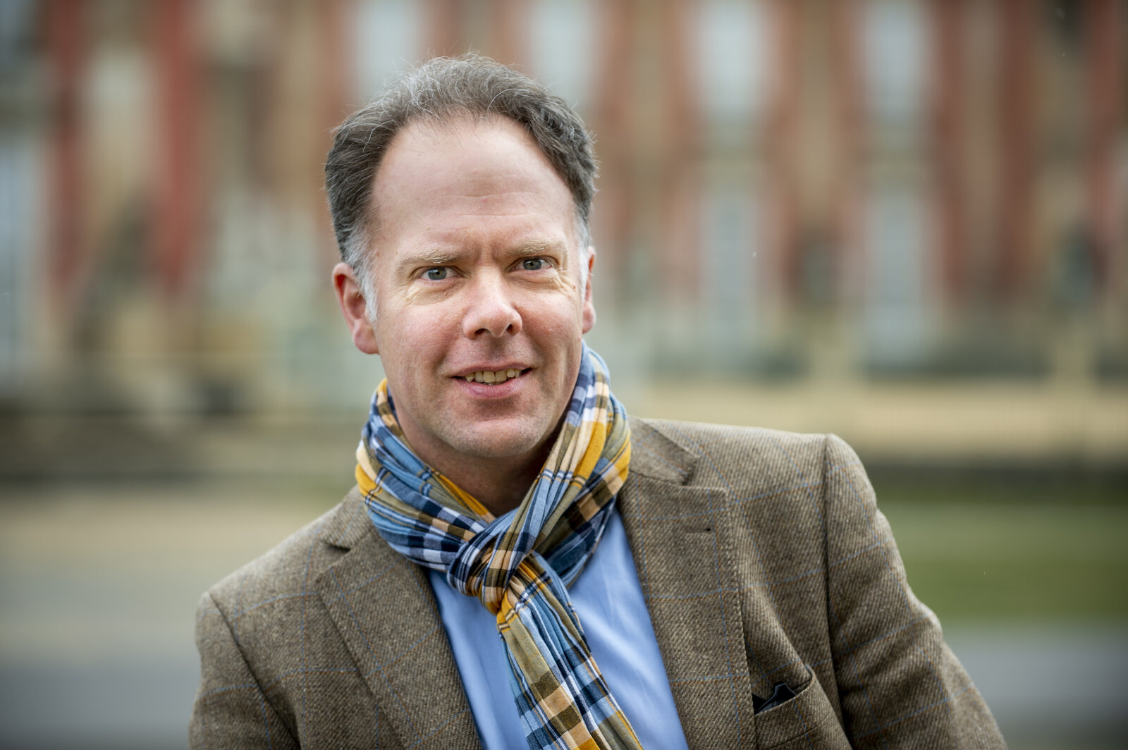 Ein Mann mit Schal lächelt.