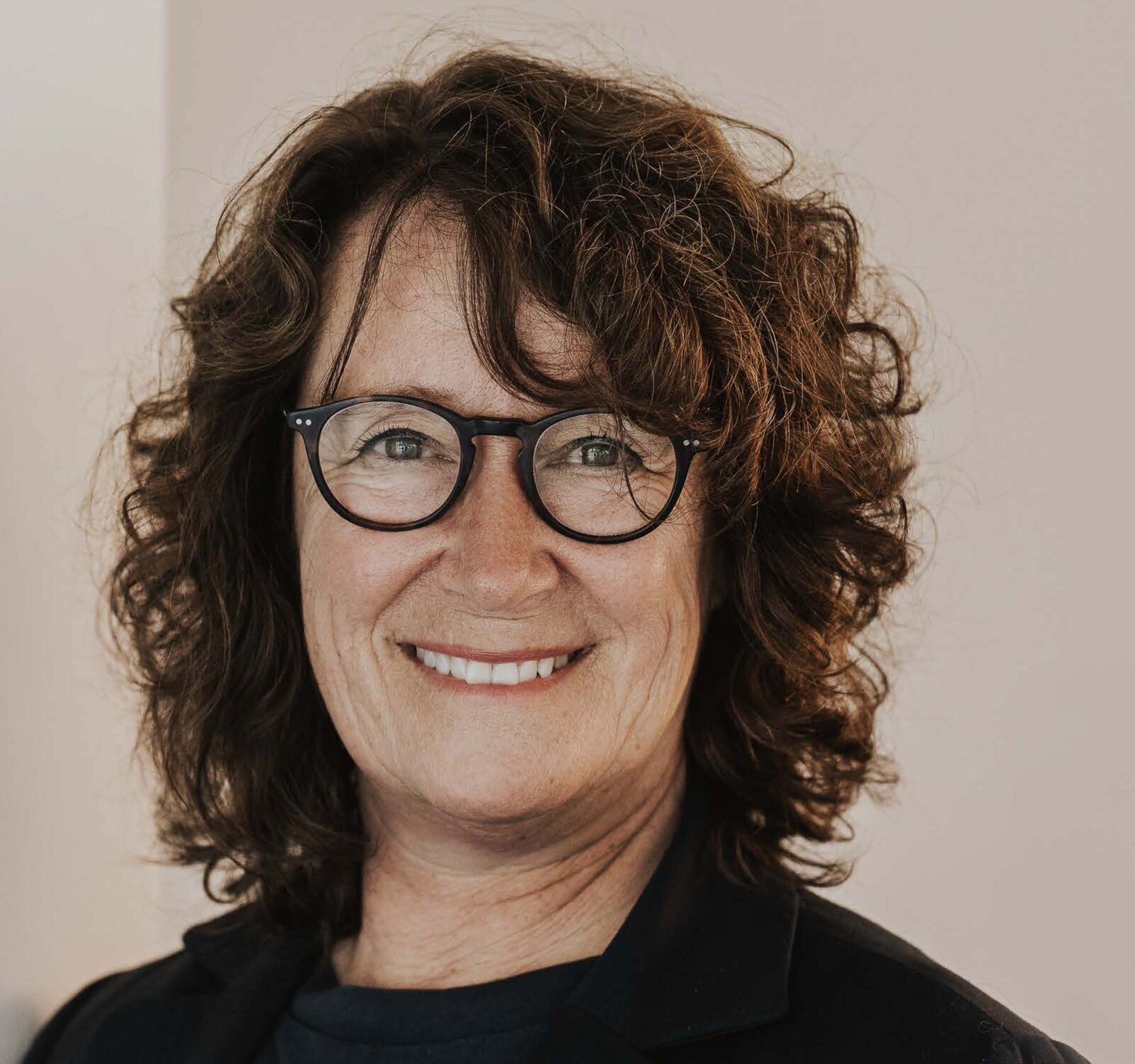 Eine Frau mit Brille lächelt in die Kamera.