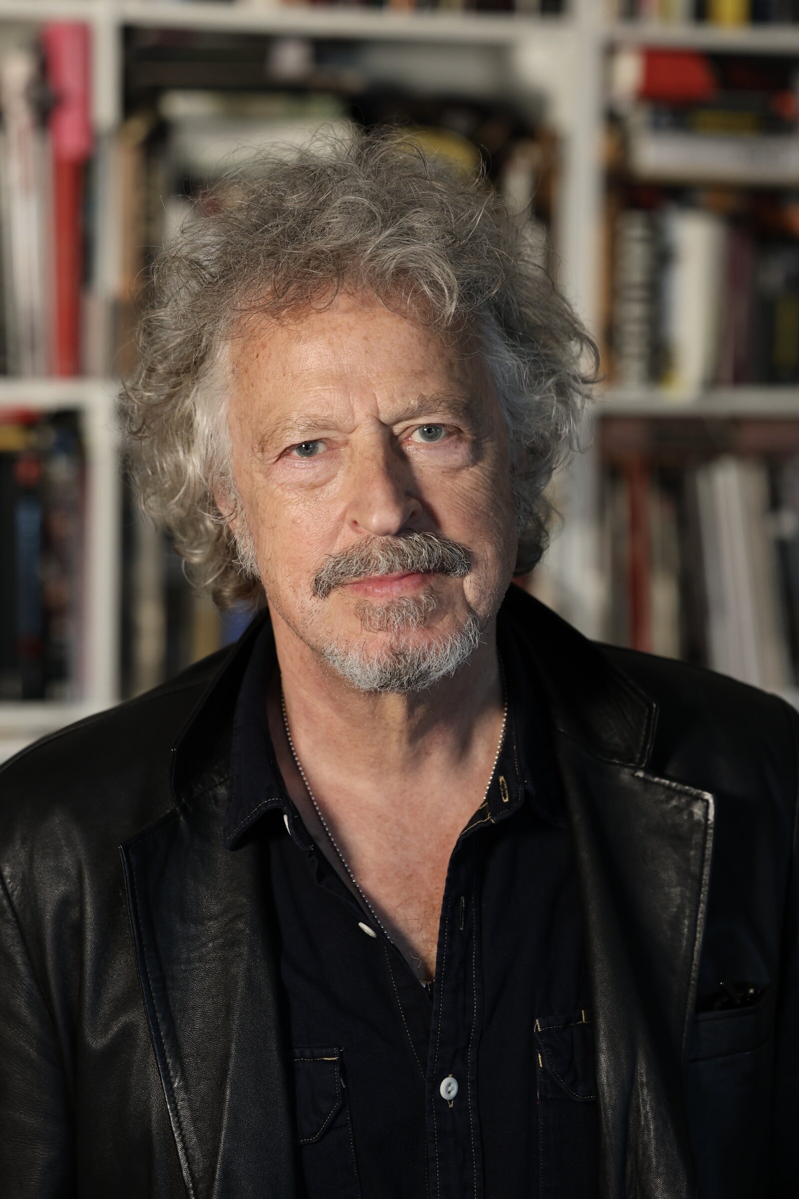 Ein Mann schaut in die Kamera. Im Hintergrund ist ein Bücherregal zu sehen.