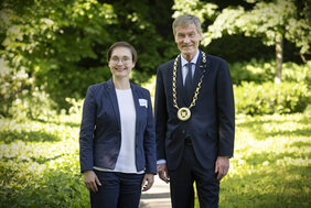 Eine Frau und ein Mann haben sich in einem Park für ein Foto aufgestellt.