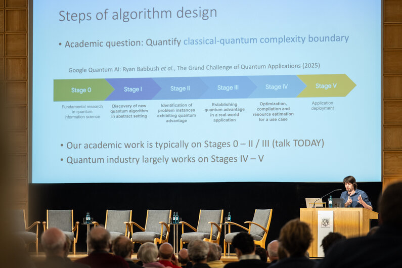 Ein Mann sitzt hier einem Rednerpult. Er gestikuliert mit den Händen.