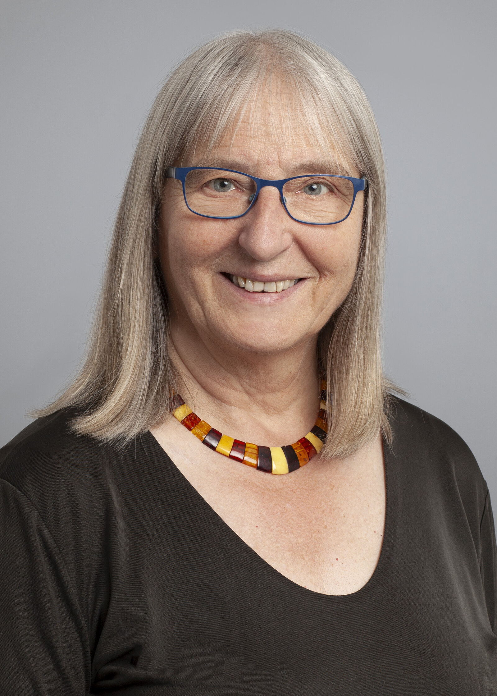 Eine Frau mit Brille und schulterlangen Haaren lächelt in die Kamera.