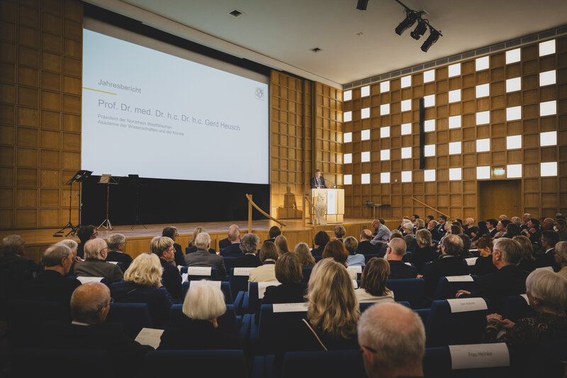 Ein Saal voller Menschen. Auf der Bühne steht ein Mann hinter einem Rednerpult.
