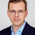 Mann mit Brille schaut freundlich in die Kamera.