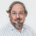 Ein Mann mit Brille und Vollbart schaut freundlichin die Kamera.