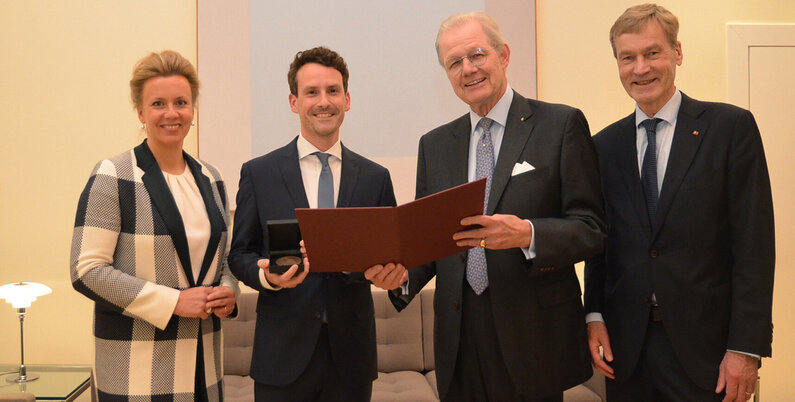 Drei Männer und eine Frau haben sich für ein Foto aufgestellt. 