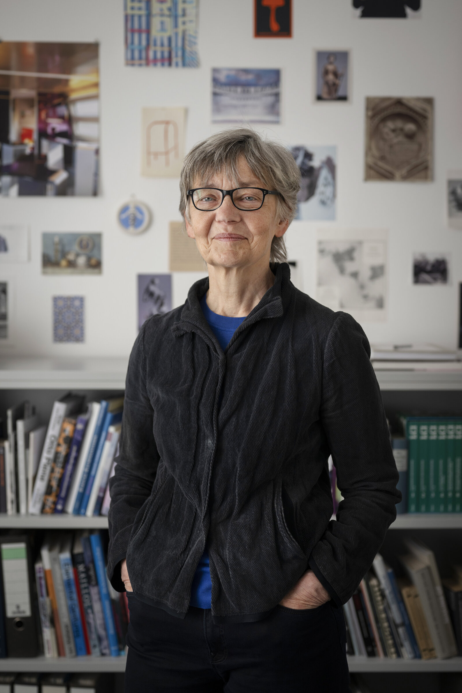 Eine Frau lächelt in die Kamera. Im Hintergrund ist ein Bücherregal zu sehen.