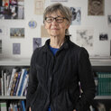 Eine Frau lächelt in die Kamera. Im Hintergrund ist ein Bücherregal zu sehen.