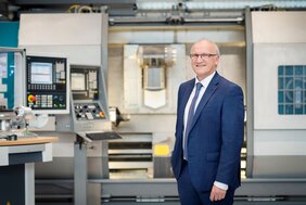 Das Bild zeigt Professor Dr. Dirk Biermann in einer Werkhalle. Im Hintergrund sind verschiedene Maschinen zu sehen. 