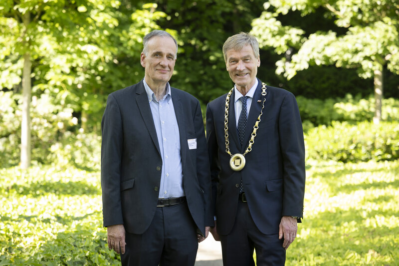 Zwei Männer haben sich in einem Garten für ein Foto aufgestellt.