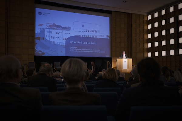 Ein gut gefüllter Veranstaltungssaal. Ein Mann hält einen Vortrag.