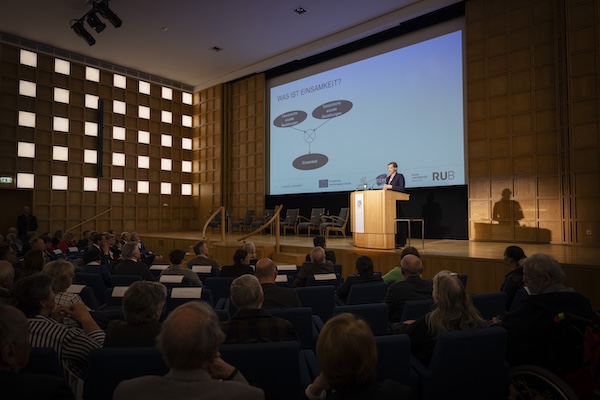 Die Einsamkeitsforscherin Prof. Dr. Maike Luhmann steht an einem Rednerpult.