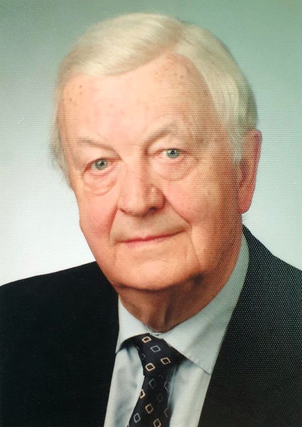 Ein Mann schaut freundlich in die Kamera. Er trägt Krawatte und eine Anzugjacke.