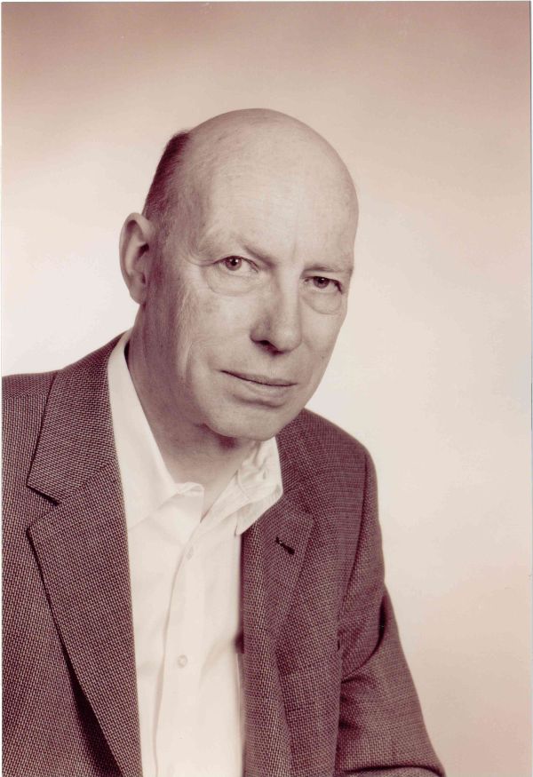 Ein Mann schaut freundlich in die Kamera. Er trägt eine Anzugjacke.