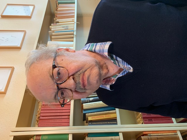 Ein Mann steht vor einem Bücherregal.