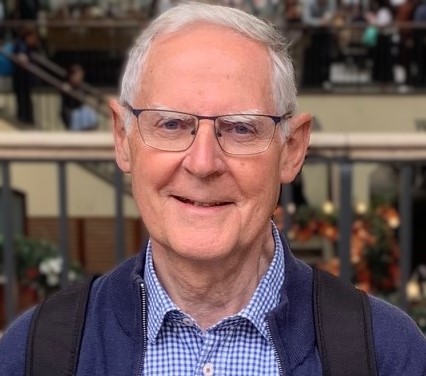 Mann mit Brille lächelt vor Treppengeländer.