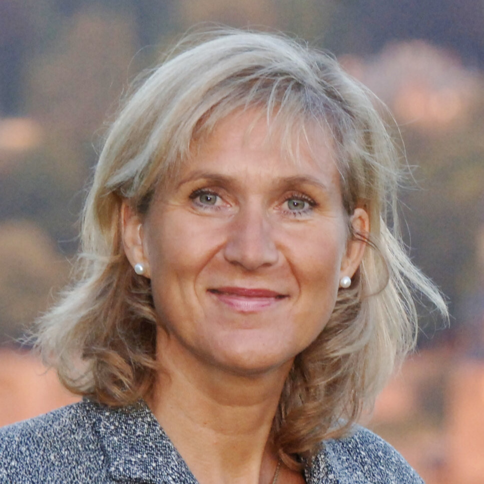 Eine Frau mit schulterlangem Haar lächelt in die Kamera.