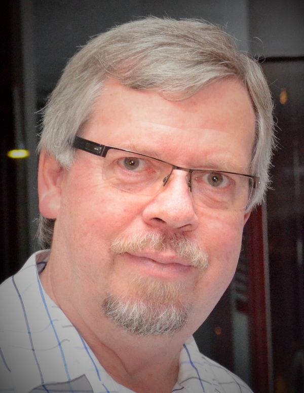 Ein Mann mit Brille schaut freundlich in die Kamera.