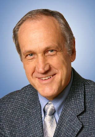 Ein Mann mit Krawatte und Anzugjacke lächelt in die Kamera.