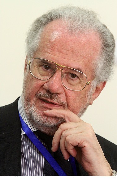 Ein Mann mit Brille fasst sich mit seiner linken Hand an sein Kinn. Er schaut freundlich in die Kamera.