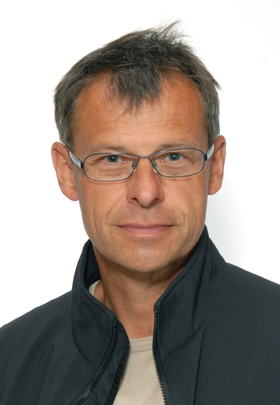 Ein Mann mit Brille schaut freundlich in die Kamera.