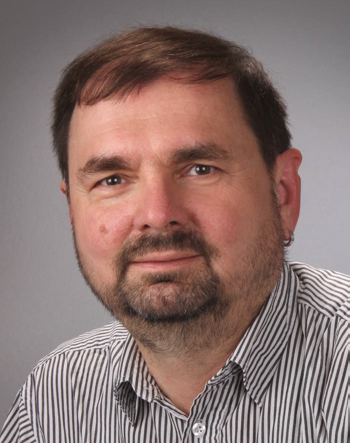 Ein Mann mit Bart lächelt in die Kamera.