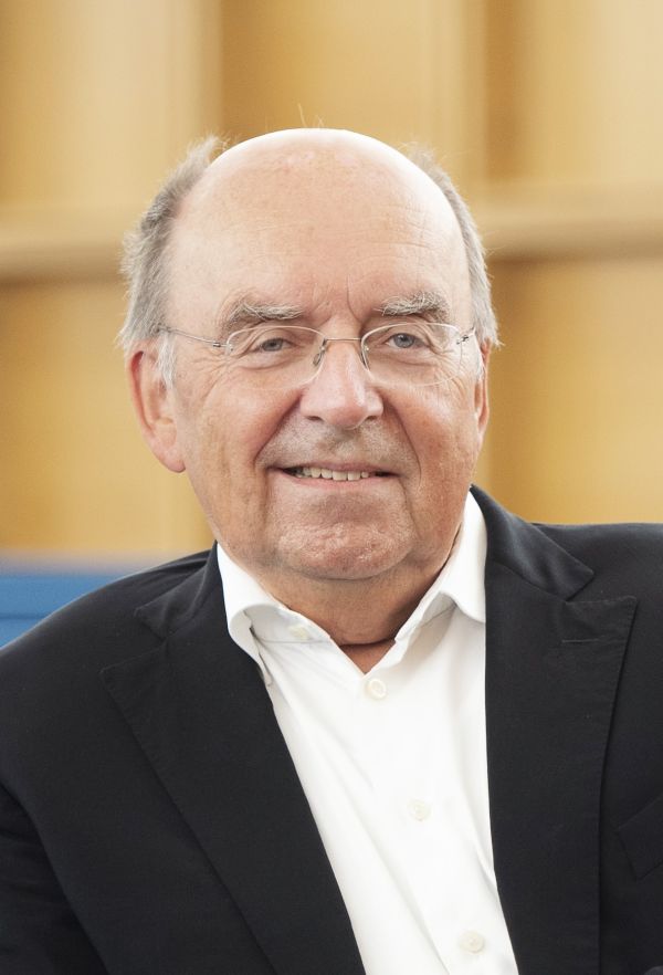 Ein Mann mit randloser Brille schaut lächelnd in die Kamera.